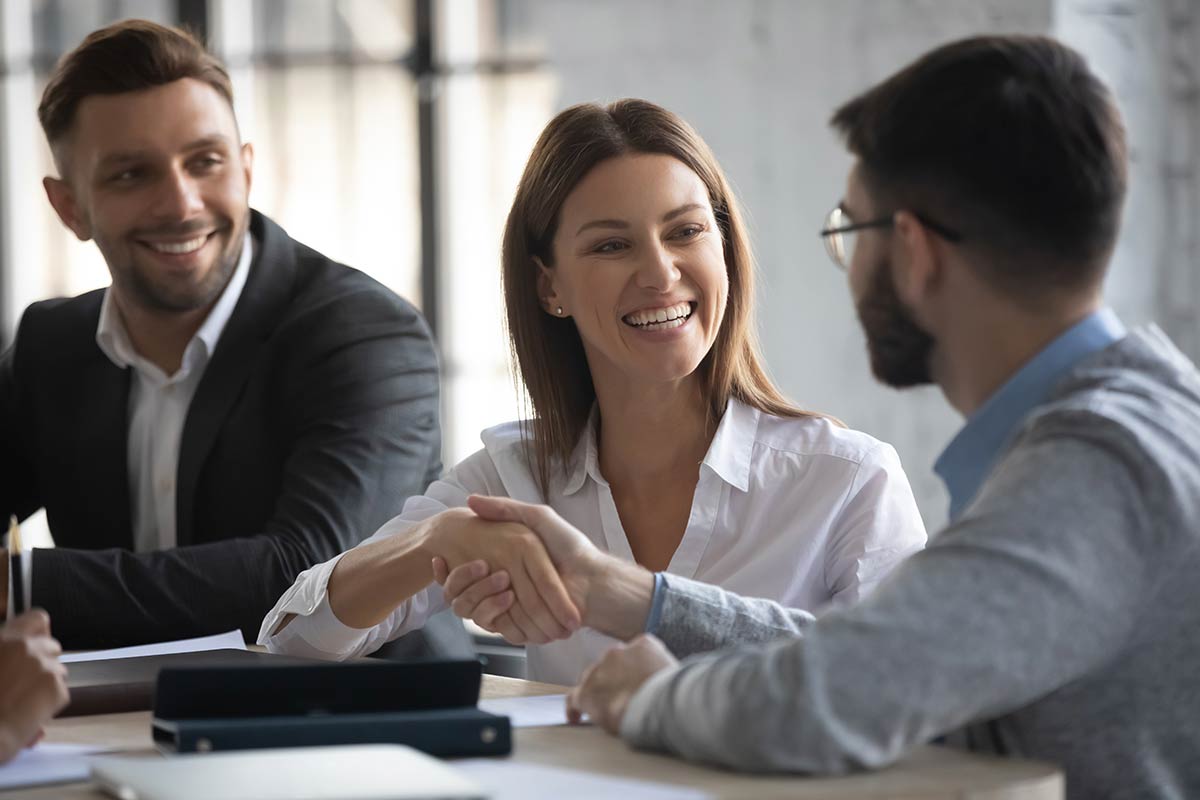 business woman shanking hands with young business man in boardroom